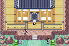 The player at the door of the Battle Arena, a wooden dojo with a dark tiled roof on a rocky rise