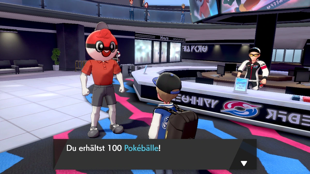 Ball Guy with his Poké Ball head in a stadium lobby in Pokémon Sword